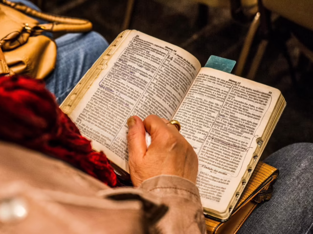 A person reading a Bible indoors, symbolizing spirituality and devotion.